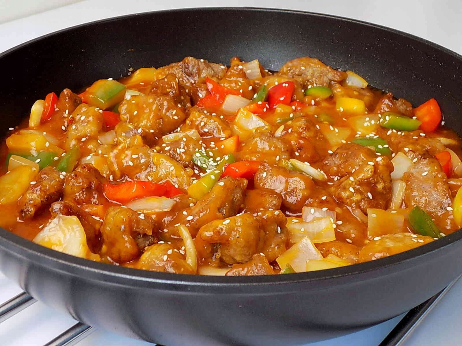 BENS ORIGINAL SOS SŁODKO-KWAŚNY Z KAWAŁKAMI ANANASA 400g 6 Wygląd pysznego dania w stylu orientalnym na patelni, zawierającego mięso, warzywa i sos, idealny na szybki obiad lub kolację.